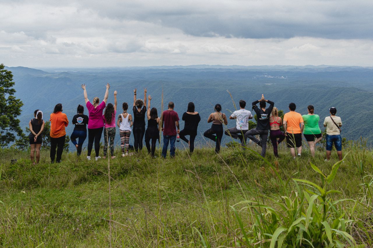 A diverse group enjoys a serene mountain view, practicing yoga outdoors together.